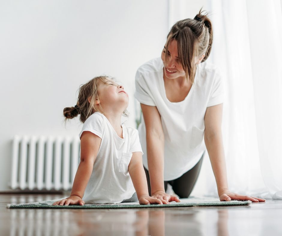 Kind und weiblich gelesene Person, die gemeinsam eine Stützhaltung üben, Bild dient zur Beschreibung des Kurses Familienyoga im Yoga und Mehr Bad Dürkheim